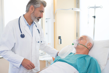 senior man inhaling through oxygen mask in clinic