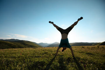  woman doing a handstand in a sunset meadow