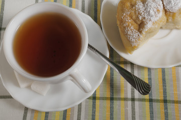 Close-up of cake and cup with tea in the background