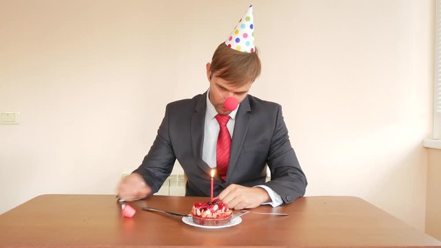 a lone man celebrates a holiday, he sits alone at a table with a cake and a candle. 4k, slow motion