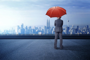 Businessman with umbrella standing with cityscape background. Business, protection, crisis concept.