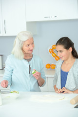 Obraz na płótnie Canvas elderly lady teaching little girl how to cook
