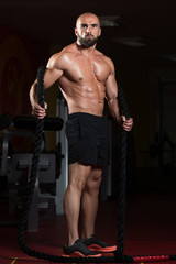 Fototapeta na wymiar Battling Ropes Young Man At Gym Workout Exercise