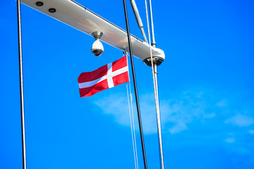 Denmark flag on ship mast, blue sky in background