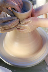 A potter teaches a child how to make a clay jar