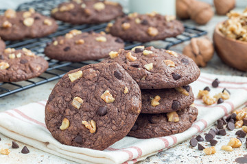 Homemade chocolate cookies with walnuts and chocolate chips on table and cooling rack, horizontal