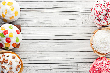 variety of cupcakes on white wooden background top view