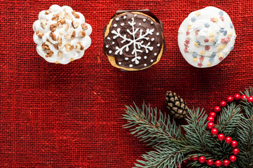 christmas decorated cupcakes at red burlap background top view