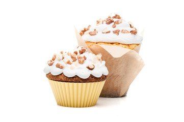 two cupcakes muffins with cream and nuts isolated at white background