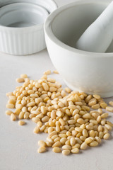 Heap of raw, uncooked pine nuts with mortar