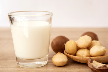 Close up the macadamia nut milk on wooden table , low fat healthy drink .