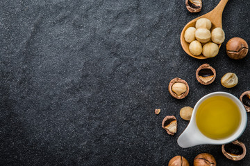 The Macadamia Nut Oil and peeled macadamia nut  on black stone , ﻿use for Healthy Skin and Hair and Natural Healing Oil Treatment , overhead and top view