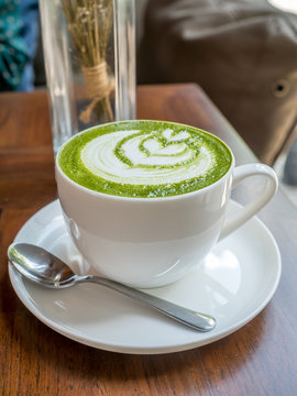 Hot green tea with milk in white cup