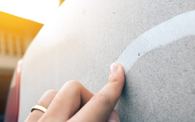 Woman hand writing on car dirt.