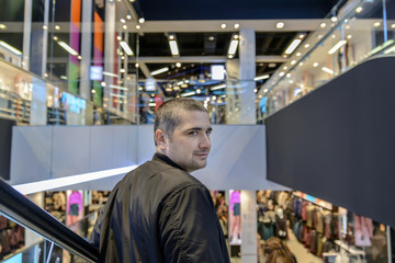 man with a short haircut rides on an escalator and smiling turns around