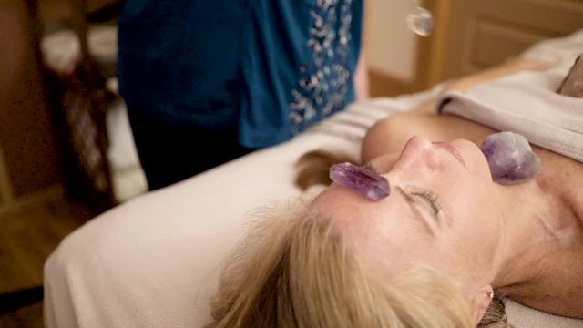 Very tight shot of therapist using a crystal pendulum over a patient&rsquo;s head for mystical healing.