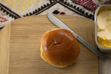 soft fluffy bun with knife on wooden board and butter spread on table