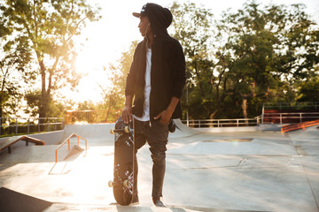 Young african man skateboarder standing