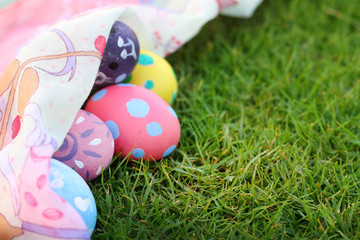 Eggs pastel colors and beautiful fabrics on grass on Easter day.