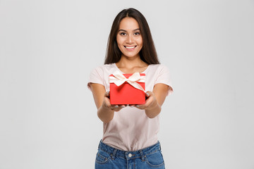 Happy young woman in casual wear giving you red gift box