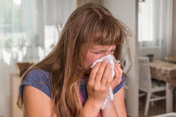 Sick woman with flu or cold sneezing into handkerchief