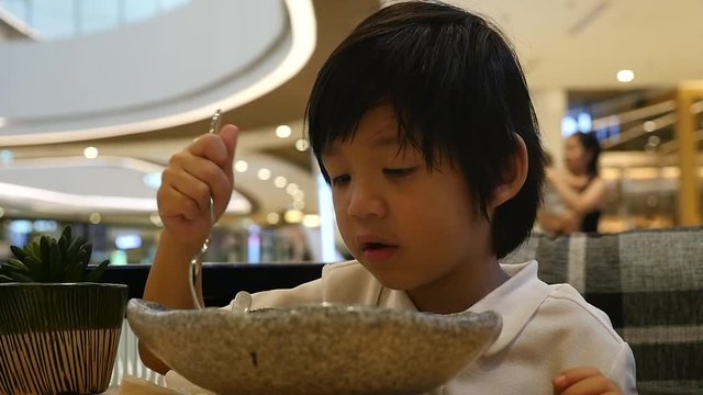Cute Asian child eating japanese noodles in a restaurant slow motion 