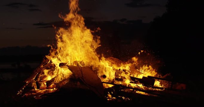Man throws wood onto Bonfire - slow motion
