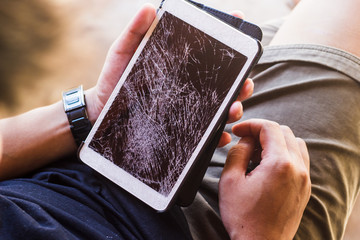 A man looking touch screen tablet or smartphone with broken screen background.