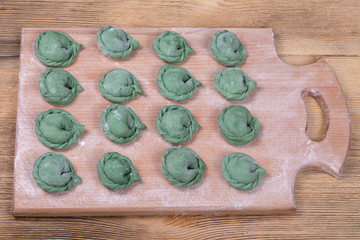 Green crude pelmeni with spirulina. Ukrainian and Russian dishes - vareniki or dumplings with beef meat or mashed potatoes or cottage cheese