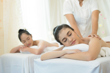 Two cute young women enjoy relaxing during massage at spa.