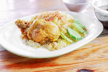 Muslim yellow rice with chicken in white dish on wooden table background.
