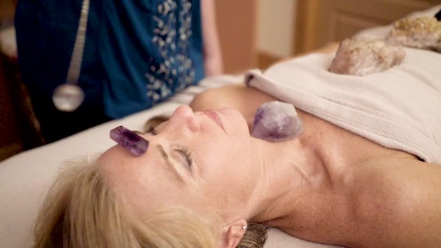Very tight shot of therapist using a crystal pendulum over a patient&rsquo;s head for mystical healing.
