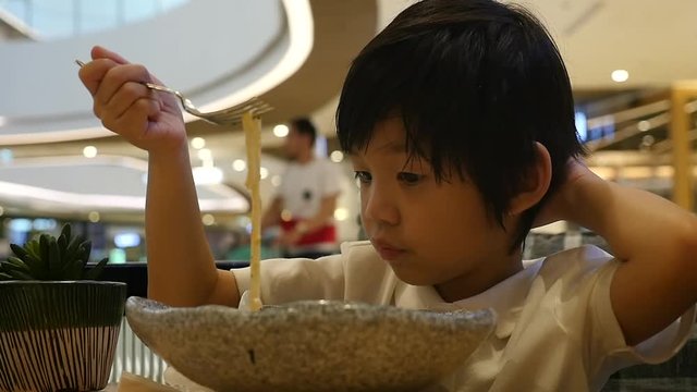 Cute Asian child eating japanese noodles in a restaurant slow motion 