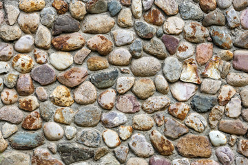 The wall of the building from the sea of boulders of different colors, round shape.