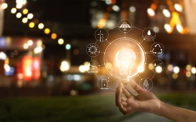 Foto op Aluminium Hand holding light bulb in front of global, show the world's consumption with icons energy sources for renewable, Ecology concept. Elements of this image furnished by NASA. © ipopba