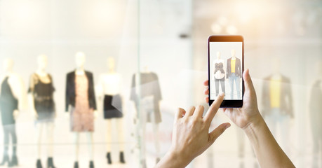 Hands using mobile smart phone and take a photo on display of a clothing store, online shopping...