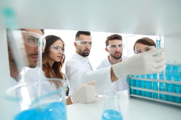 background image is a group of microbiologists studying the liquid in the glass tube.