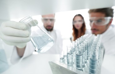 closeup.a group of scientists studying the liquid in the glass tube