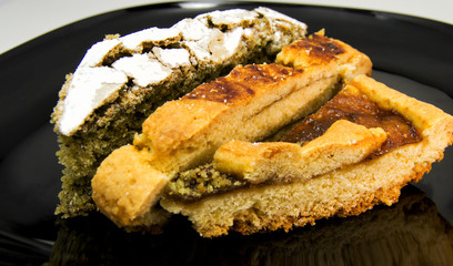 Slices of three different homemade tarts and pie on a black dish. For food concepts