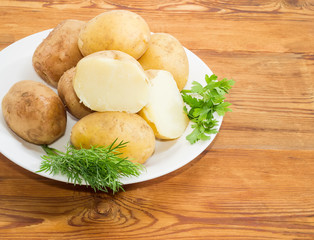 Potatoes boiled in their skins and herbs on dish closeup