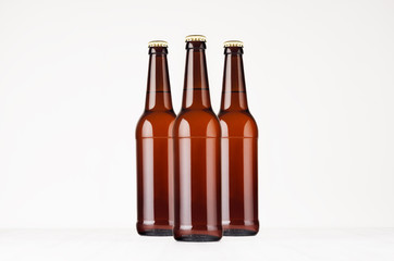 Group brown longneck beer bottles 500ml mock up. Template for advertising, design, branding identity on white wood table.