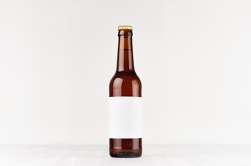 Brown longneck beer bottle 330ml with blank white label on white wooden board, mock up. Template for advertising, design, branding identity.