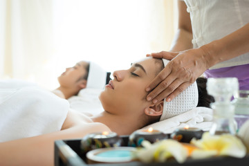 Young beautiful woman having face massage relaxing in spa.