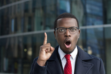 Urban portrait of emotional African American businessman pictured in city center looking at camera...