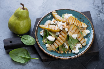 Salad with fresh spinach leaves, grilled pears and feta cheese, studio shot