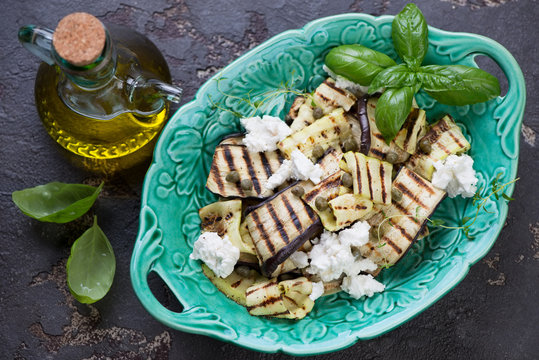Grilled slices of eggplants and zucchini with olive oil, capers and cheese, view from above