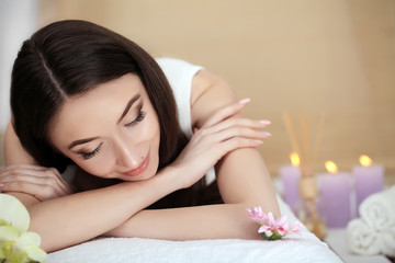 Fototapeta na wymiar Beautiful young woman lying on massage table in spa salon