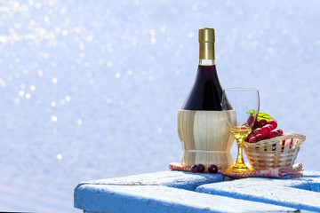 Bottle of wine  with wineglass and basket with grapes on tabel by beach