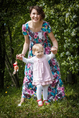 Mother and daughter have fun in the park and apple tree with white flowers