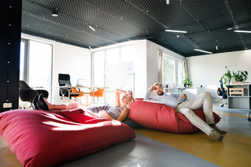 Business people in the office sitting in bean bags. - Powered by Adobe